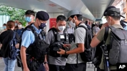 FILE -Police officers stop and check journalists near the Convention and Exhibition Center, where Chinese President Xi Jinping will attend a ceremony in Hong Kong, July 1, 2022.
