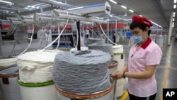 FILE - A worker watches as a machine processes cotton yarn at a Huafu Fashion plant, as seen during a government organized trip for foreign journalists, in Aksu in western China's Xinjiang Uyghur Autonomous Region, April 20, 2021.