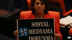 FILE - A lawmaker from the main opposition Republican People's Party holds up a placard that reads "Don't touch my social media" in protest at the parliament, in Ankara, Turkey, Oct. 11, 2022.