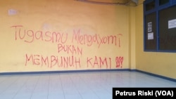 Bentuk protes suporter atas sikap represif aparat dalam menangani kericuhan pada 1 Oktober 2022 tertulis pada tembok stadion Kanjuruhan di Malang, Jawa Timur. Foto diambil pada 4 Oktober 2022. (Foto: VOA/Petrus Riski)