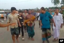 Dalam gambar yang dibuat dari video ini, seorang pria membawa jenazah korban di Panchagarh, Bangladesh, Minggu, 25 September 2022. Sebuah perahu yang membawa sekitar 100 peziarah Hindu terbalik pada Minggu di sebuah sungai di Bangladesh utara, kata polisi. (AP)
