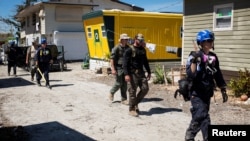 Federal Emergency Management Agency personnel and Lee County Sheriff officers walk through a trailer park after Hurricane Ian caused widespread destruction, in Fort Myers Beach, Florida, Oct. 3, 2022.