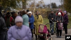 People wait in line as humanitarian aid is distributed at the village of Mykhailo Lukasheve, in Zaporizhzhia region, Ukraine, Oct. 20, 2022. 