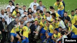 FILE - Brazil's President Jair Bolsonaro and Brazil players celebrate winning the Copa America with the trophy, Maracana Stadium, Rio de Janeiro, July 7, 2019. 