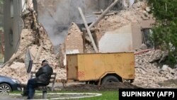 Seorang penduduk lokal duduk di luar sebuah bangunan yang dihancurkan oleh pesawat tak berawak Rusia, buatan Iran, setelah serangan udara di Bila Tserkva, barat daya Kyiv, pada 5 Oktober 2022. (Foto: AFP)