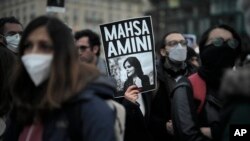FILE - A woman shows a placard with a photo of of Iranian Mahsa Amini as she attends a protest against her death, in Berlin, Sept. 28, 2022. Amini's death in custody has sparked a stunning wave of protests across Iran.
