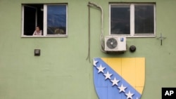 A woman looks out of the window in Sarajevo, Bosnia, Oct. 12, 2022.The European Union's executive is advising member states to grant Bosnia-Herzegovina candidate member status despite continuing criticism of the way the Balkan nation is run.