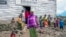 FILE - Pasika Bagerimana stands outside a temporary shelter she shares with others who fled fighting, in Nyiragongo, Democratic Republic of Congo, Aug. 31, 2022. Increased violence in the DRC is leading to a surge of refugees crossing the border into Uganda.