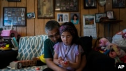 Alfred Ningeulook, 61, hugs his granddaughter, Glenna, 6, in his home in Shishmaref, Alaska, Sunday, Oct. 2, 2022. Rising sea levels, flooding, increased erosion and loss of protective sea ice and land have led residents of this island community to vote twice to relocate. 