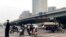 People ride scooters at an intersection near a bridge where social media videos earlier appeared to show smoke and protest banners in Beijing, Oct. 13, 2022. 