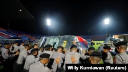Aparat kepolisian mendorong kendaraan yang rusak saat akan memindahkannya keluar dari Stadion Kanjuruhan, tempat terjadi kerusuhan dan kericuhan usai pertandingan sepak bola antara Arema vs Persebaya, di Malang, Jawa Timur, 2 Oktober 2022. (Foto: REUTERS/