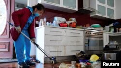 Xuan Nguyen cleans up inside a damaged home following severe flooding in the Maribyrnong suburb of Melbourne, Australia, Oct. 17, 2022. 
