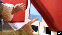 FILE — A woman fills out her ballot as she holds her daughter on Nov. 3, 2020, in Nashville, Tenn. 