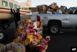 Bering Air agent Denis Sinnok shuts the door of a Cessna plane at the air strip after unloading the dozens of boxes of Eggo waffles and other goods in Shishmaref, Alaska, Thursday, Oct. 6, 2022.