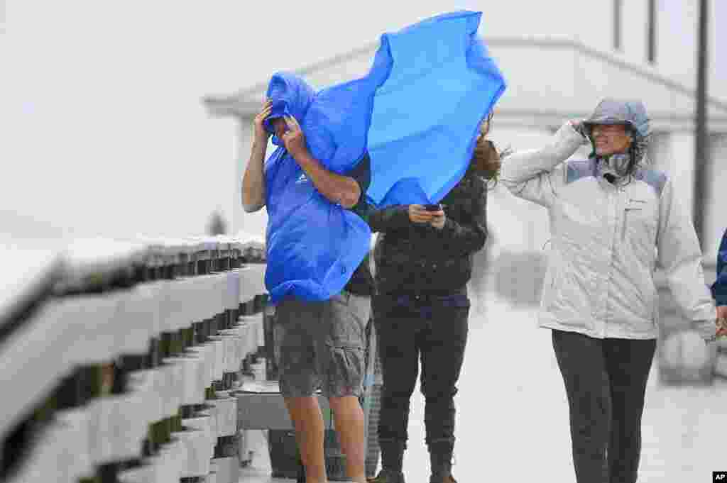People walk on the Ballast Point Pier ahead of Hurricane Ian, Sept. 28, 2022, in Tampa, Florida.