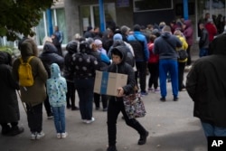 A woman carries a box as humanitarian aid is distributed at the village of Mykhailo Lukasheve, in Zaporizhzhia region, Ukraine, Oct. 20, 2022.