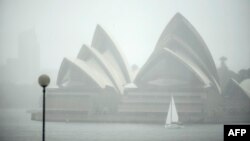 A yacht sails next to the Opera House while it rains in Sydney on Oct. 6, 2022. 