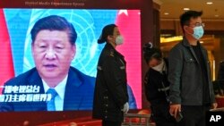A security personnel checks a journalist near a TV screen showing image of President Xi Jinping at a media hotel in Beijing, Oct. 21, 2022.