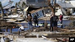 Orang-orang berdiri di jembatan yang hancur ke Pulau Pinus saat mereka melihat kerusakan yang disebabkan oleh Badai Ian di Matlacha, Florida, pada hari Minggu, 2 Oktober 2022. (Foto: AP/Gerald Herbert)