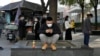 A man looks at his phone near a line for COVID tests in Beijing, Oct. 24, 2022. China's economic growth picked up in the latest quarter but still was among the weakest in decades as the ruling Communist Party tries to reverse an economic slump.