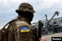 FILE - A Ukrainian serviceman stands in front of silos of grain at Odesa Black Sea port, in Odesa, Ukraine, July 29, 2022. On Oct. 29, Russia ended a U.N.-brokered deal allowing Ukraine to export grain by sea.