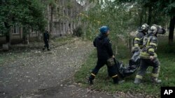 Ukrajinske spasilačke ekipe odnose telo žene posle ruskog napada na školu u oblasti Luganska, 28. septembar 2022.