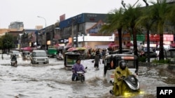 អ្នក​ដំណើរ​ជិះ​យានជំនិះ​កាត់​ផ្លូវ​លិចទឹក​មួយ​ក្នុង​រាជធានី​ភ្នំពេញ កាល​ពី​ថ្ងៃទី ២៦ ខែកញ្ញា ឆ្នាំ២០២២ ក្រោយ​ពី​មាន​ភ្លៀង​ធ្លាក់​ខ្លាំង។ (Photo by TANG CHHIN Sothy / AFP)