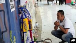 A man prays for the victims of Saturday's soccer match stampede in front of gate 13 the Kanjuruhan Stadium in Malang, Indonesia, Oct. 4, 2022. A police chief and nine elite officers were removed from their posts Monday and 18 others were being investigate for responsibility in the firing of tear gas inside a soccer stadium that set off the stampede that killed more than 100 people, officials said.