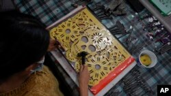 A woman uses a plastic stencil to make “papel picado”, the traditional manufacture of tissue paper cut-out decorations long used in altars for the Day of the Dead, in a workshop in Xochimilco, a borough of Mexico City, Oct. 27, 2022. 