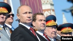 Presiden Rusia Vladimir Putin (depan, kiri) dan PM Dmitry Medvedev (tengah) mengamati parade Hari Kemenangan di Lapangan Merah, Moskow (9/5).