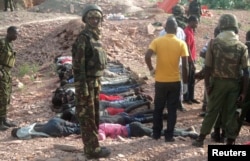 FILE - Kenyan military personnel stand near bodies lined up on the ground at a quarry site where attackers killed at least 36 workers in a village in Korome, outside the border town of Mandera, Dec. 2, 2014.