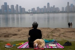FILE - A child wearing a mask to protect against the coronavirus rests on the bank of the Yangtze River in Wuhan in central China's Hubei province, April 16, 2020.