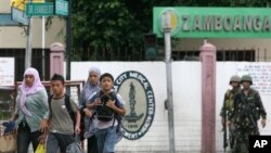 Warga desa setempat berupanya menyelamatkan diri dan mengungsi pasca bentrokan antara patroli angkatan laut Filipina dengan front pembebasan Islam Moro di kota Zamboanga, selatan Filipina (9/9). 