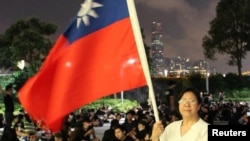 Protester Yung Xiu Kwan, 67, poses for picture with a Taiwan flag during a demonstration against the proposed extradition bill, in Hong Kong, China June 17, 2019. REUTERS/Jessie Pang