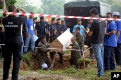 FILE - Malaysian officials provide Muslim burial to 21 human trafficking victims, believed to be Rohingya Muslim refugees, found in shallow graves in jungles bordering Thailand, in Kedah, Malaysia, June 22, 2015.