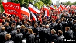 FILE - Riot police watch as far-right supporters take part in anti-refugee rally in Dortmund, Germany, June 4, 2016. The placard in front reads "Stop the flood of asylum seekers."