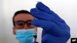 Zdravstveni radnik priprema dozu vakcine AstraZeneka, tokom vakcinacije u prihvatnom centru za izbeglice "Krnjača", u blizini Beograda, Srbija, 26. marta 2021. (Foto: AP/Darko Vojinović)