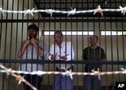 FILE - Aung Naing Soe, left, Burmese freelance journalist and interpreter; Hla Tin, Burmese driver; and Lau Hon Meng, Singaporean journalist stand for their first court appearance after being accused of flying drones illegally over parliament buildings, in Naypyitaw, Myanmar, Nov. 10, 2017.