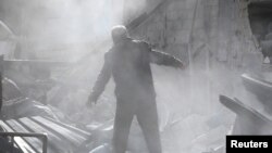 Seorang pria berdiri di reruntuhan bangunan yang hancur pasca serangan udara di kota Mesraba yang dikuasai pemberontak di pinggiran timur Damaskus Ghouta, Suriah, 26 November 2017.