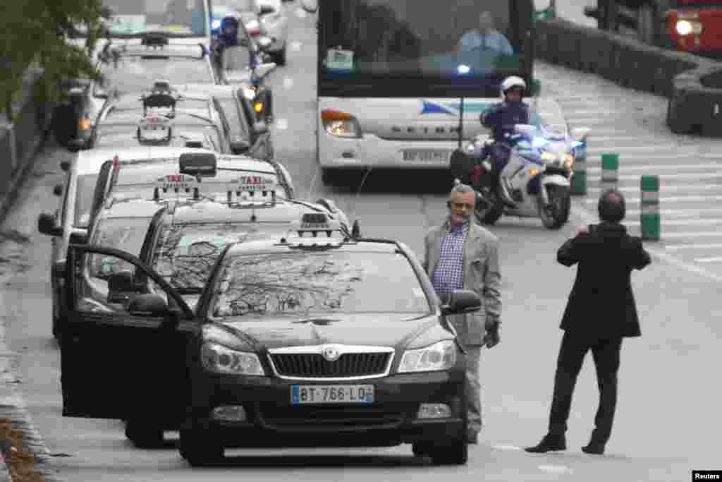 French motorcycle police escort striking Paris taxis which take part in a demonstration over the Paris ring road, Dec. 15, 2014. 