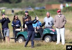 Donald Trump, right, then a presidential candidate, watches England's Charley Hull play her shot on the 16th fairway on the first day of the Women's British Open golf championship on the Turnberry golf course in Scotland, July 30, 2015.