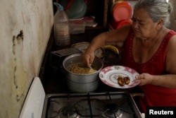 Antonia Torres, mother of Yuni Perez, cooks for seven people a packet of pasta received in a CLAP box, a Venezuelan government handout of basic food supplies, in her home at the slum of Petare in Caracas, March 9, 2018.