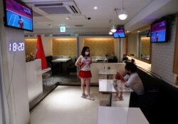 Seorang pelayan mengenakan masker di tengah pandemi COVID-19, berbicara dengan seorang pelanggan di bar 'Cheers One' Tokyo, Jepang, yang sepi pengunjung, 29 Juli 2021. (REUTERS/Kim Kyung-Hoon)