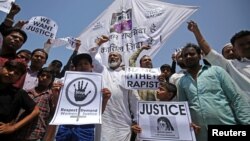 FILE - People hold placards at a rally condemning the rapes of two girls, aged 8 and 11, in Ahmedabad, India, April 22, 2018.