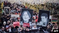 Russian opposition protestors march in central Moscow, Jan. 19, 2020, carrying portraits of lawyer Stanislav Markelov and journalist Anastasia Baburova.