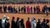 FILE - People affected by the coronavirus economic downturn line up to receive food aid in Pretoria, South Africa, May 20, 2020.
