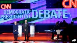 Democratic presidential candidates Hillary Clinton, left, and Senator Bernie Sanders, Independent-Vermont, take the stage before a Democratic presidential primary debate at the University of Michigan-Flint, Sunday, March 6, 2016, in Flint, Michigan.
