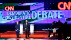 បេក្ខជន​ប្រធានាធិបតី​លោក​ស្រី​ Hillary Clinton (ឆ្វេង)​ និង​លោក Bernie Sanders ឈរ​នៅ​លើ​ឆាក​មុន​ពេលការពិភាក្សា​ដេញ​ដោល​បឋម​នៅ​សាកល​វិទ្យាល័យ​ Michigan-Flint កា​ល​ពី​ថ្ងៃ​អាទិត្យ​ទី​០៦​ កុម្ភៈ ២០១៦​ នៅ​ទីក្រុង​​ Flint រដ្ឋ Michigan។