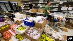 Volunteer David Bril, 13, puts together client Charles Scott's food selection, at the Mitzvah Food Project pantry at the Jewish Federation of Greater Philadelphia Digital Choice Food Program in Philadelphia, Pennsylvania, July 1, 2015.