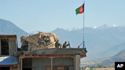 FILE - Two Afghan soldiers sit on a guard tower at a military base in Kunar province, Afghanistan, June 1, 2013.